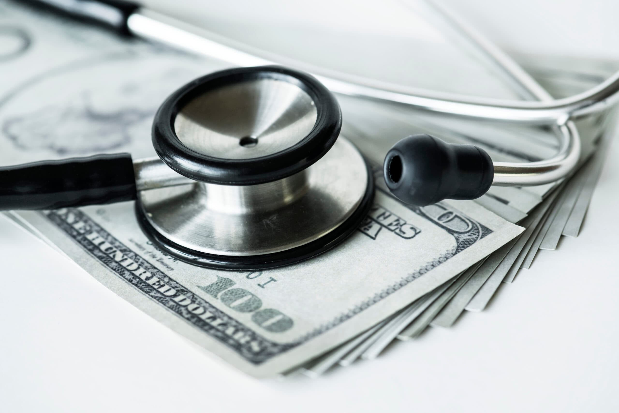 closeup-cash-stethoscope-healthcare-expenses-concept-scaled